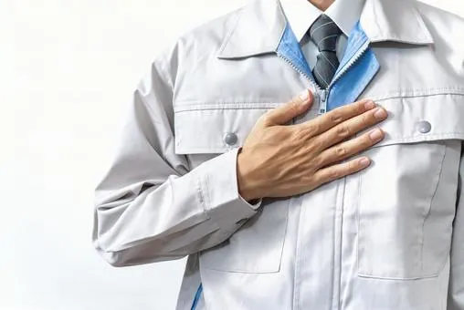 作業着を着た人が胸に手を当てている画像